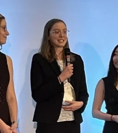 Sarah Beth speaking on a panel, holding a microphone, flanked by fellow founders.